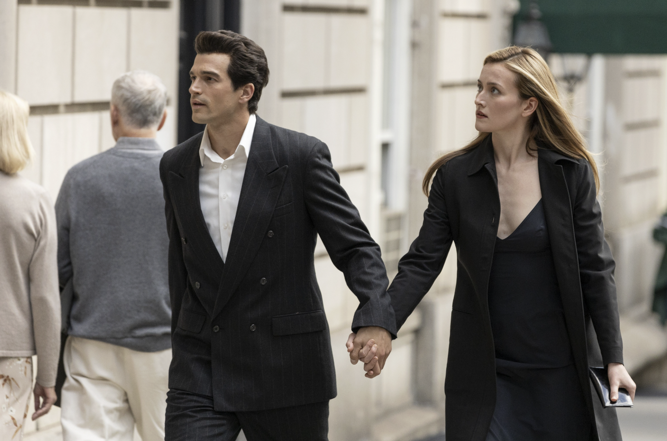 &laquo; Photographie des acteurs interpr&eacute;tant le couple Kennedy-Bessette dans la s&eacute;rie "Love Story" (Disney+, f&eacute;vrier 2026). L'actrice incarnant Carolyn porte une robe minimaliste noire assortie d'une veste structur&eacute;e et d'une pochette sobre, tandis que l'acteur jouant John F. Kennedy Jr. figure &agrave; ses c&ocirc;t&eacute;s. Ce visuel symbolise l'esth&eacute;tique Calvin Klein des ann&eacute;es 90, moteur de l'explosion des requ&ecirc;tes Google sur le luxe discret ce mois-ci. &raquo;